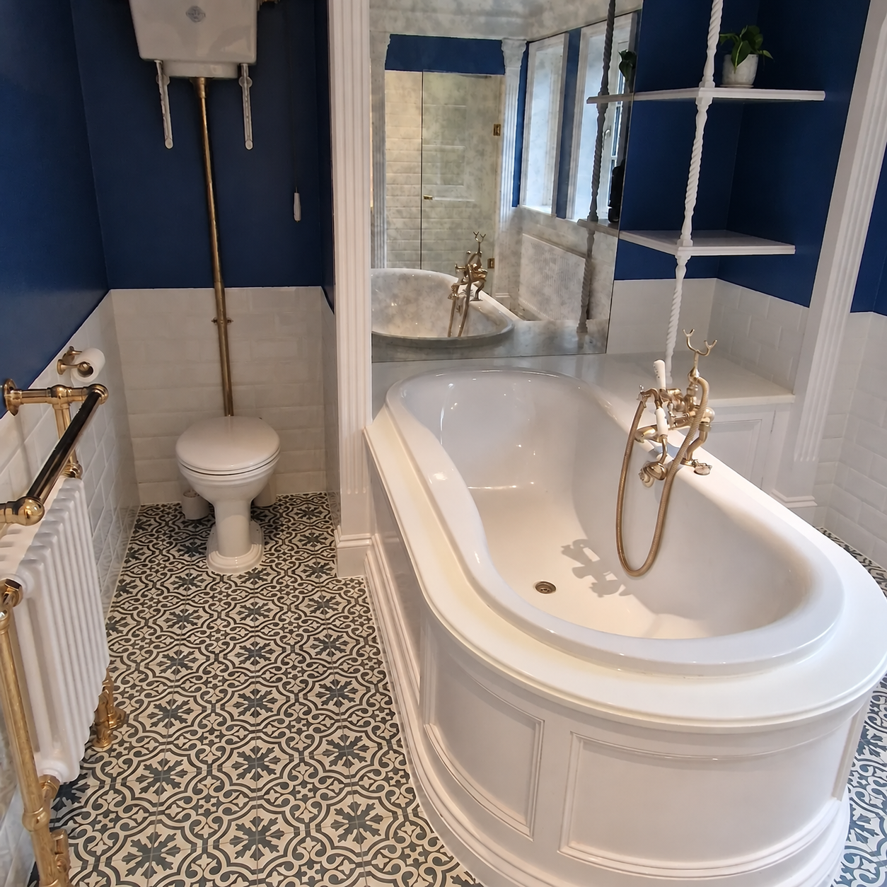 Classic bathroom with navy walls, a white bathtub, brass fittings and patterned floor tiles