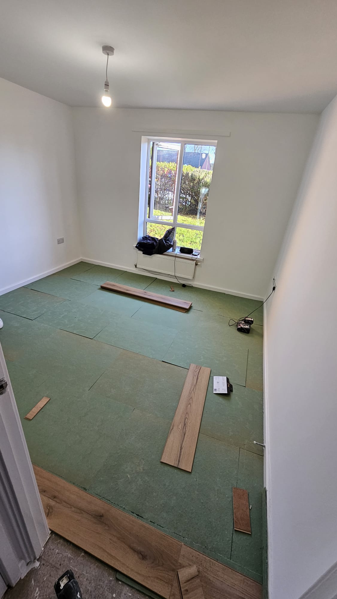 The room before floor installation, with green underlay laid out