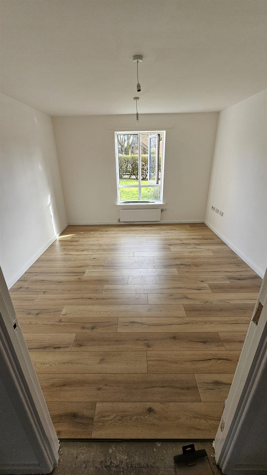 Refurbished room with a newly laid wood-effect floor and freshly painted white walls