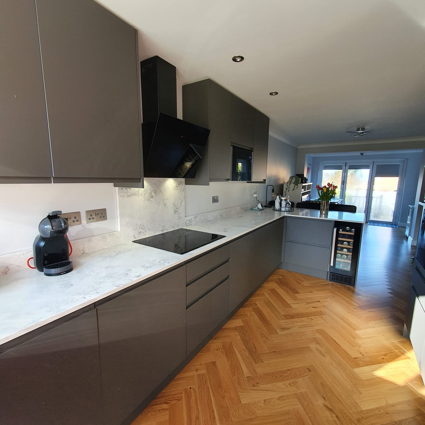 NEPTI kitchen with grey cabinets, light marble-effect worktops and herringbone wood flooring